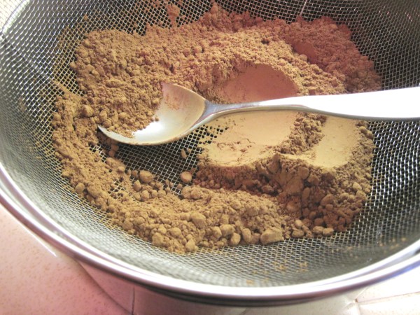 Sifting cocoa through a mesh strainer
